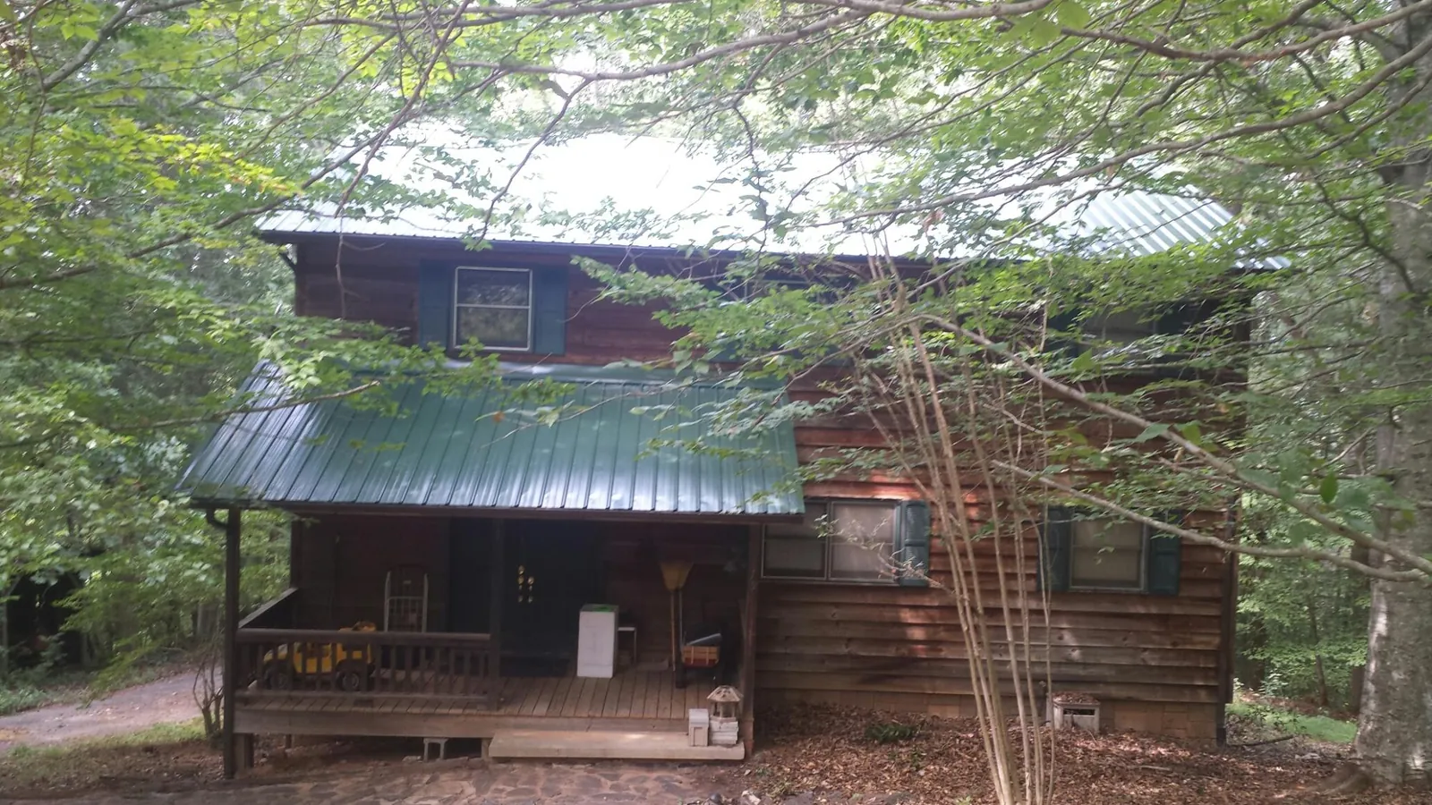 Green metal roof and covered porch on a log cabin in Lancaster